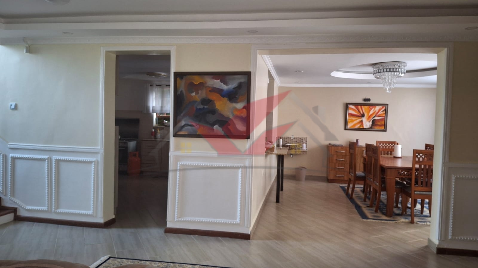 Spacious living room with large wooden bay windows overlooking a landscaped garden, featuring chandelier lighting and chimney in a 4 bedroom house for sale in Karen