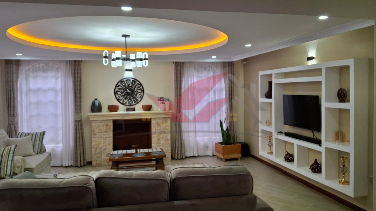 Spacious living room with large wooden bay windows overlooking a landscaped garden, featuring chandelier lighting in a 4 bedroom house for sale in Karen